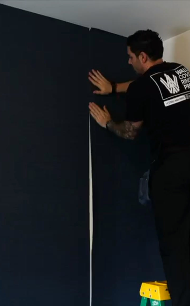 Wallcovering Pro installer smoothing a freshly hung wallcovering panel
