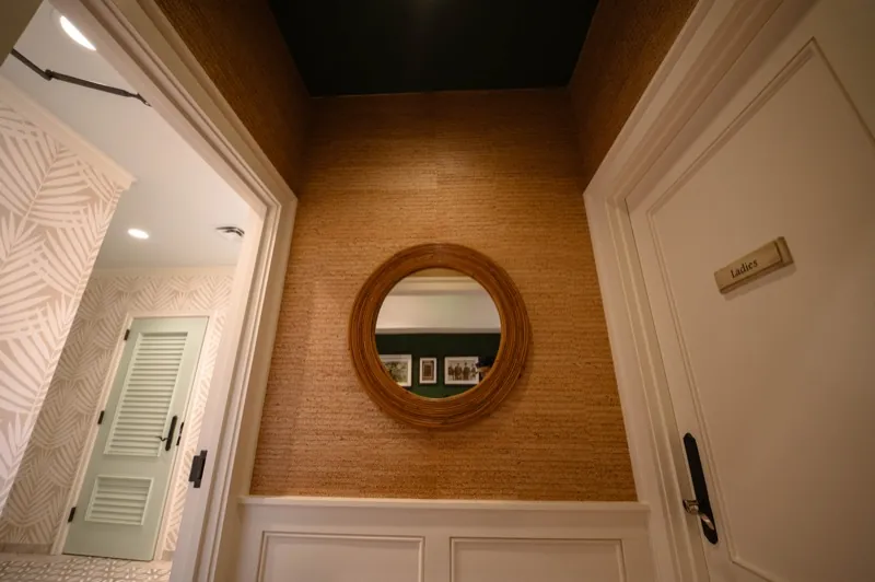 Card Sound Clubhouse powder room with a round mirror and grasscloth wallcovering, installed by Wallcovering Pro